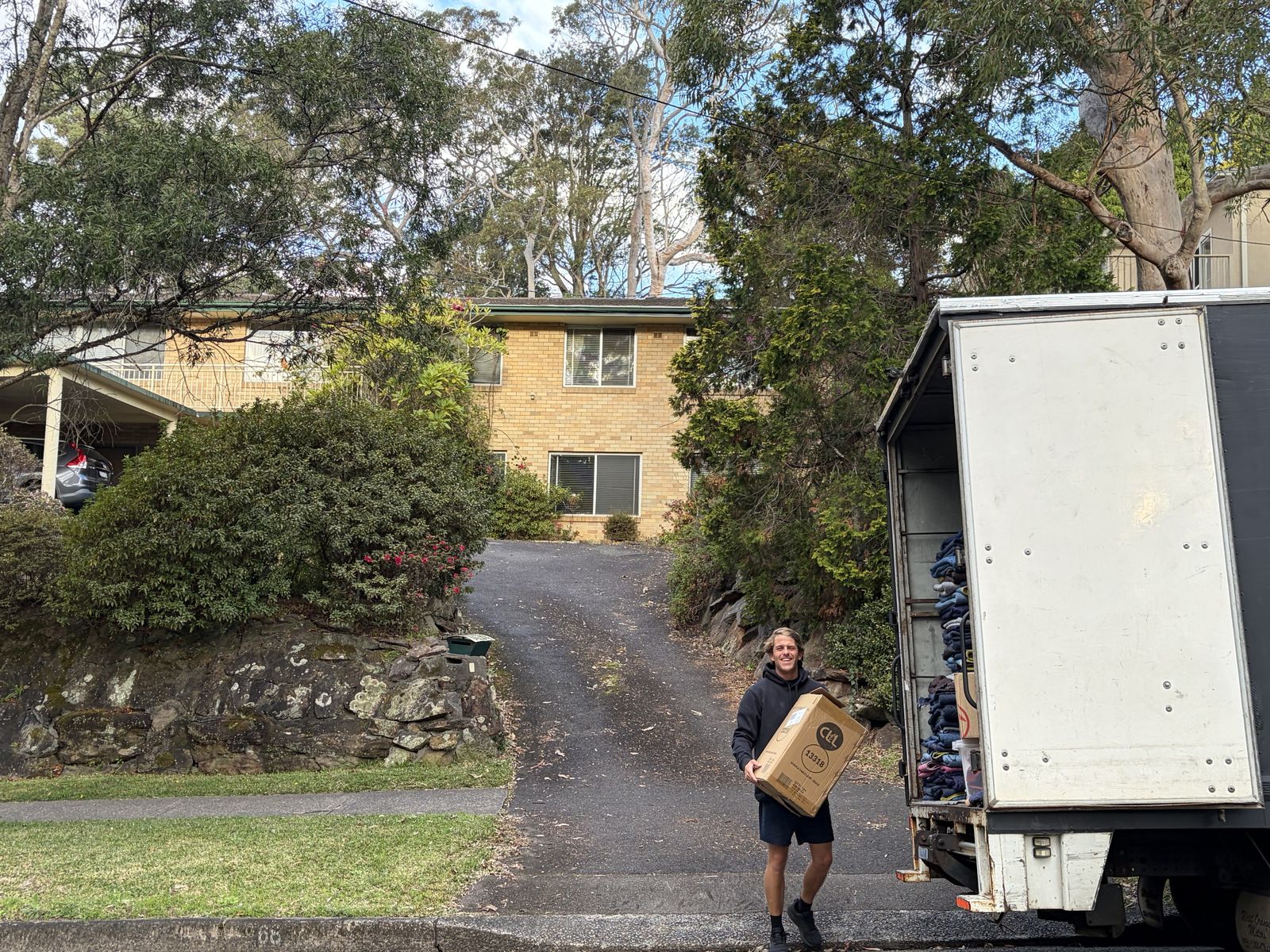 Billy carrying a box down a driveway to the truck
