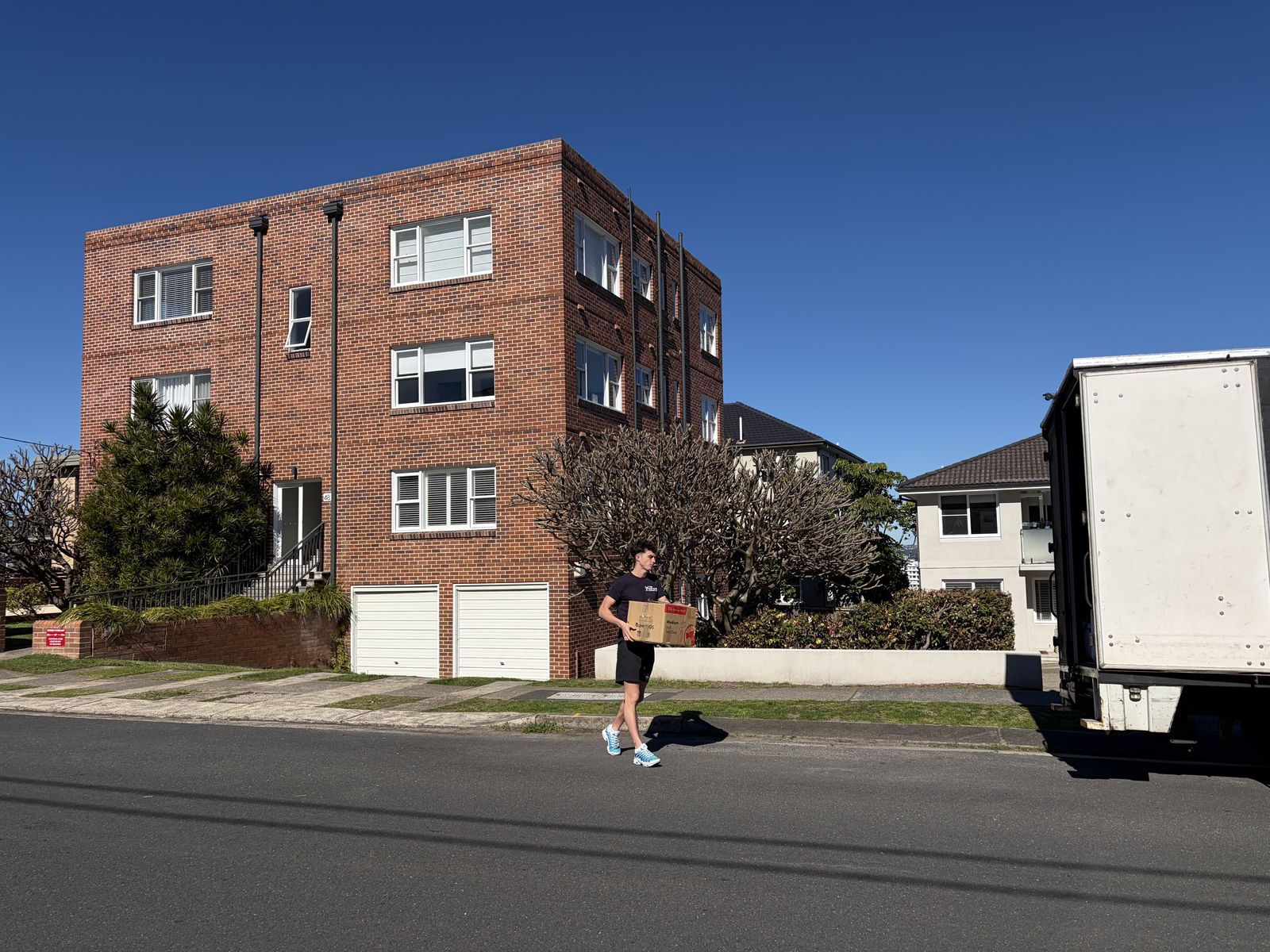 Jet carrying a box past a brick apartment building